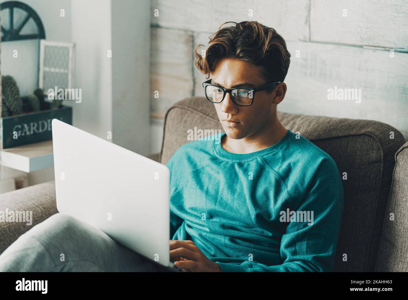 Student boy using at home a laptop sitting on the sofa with ...