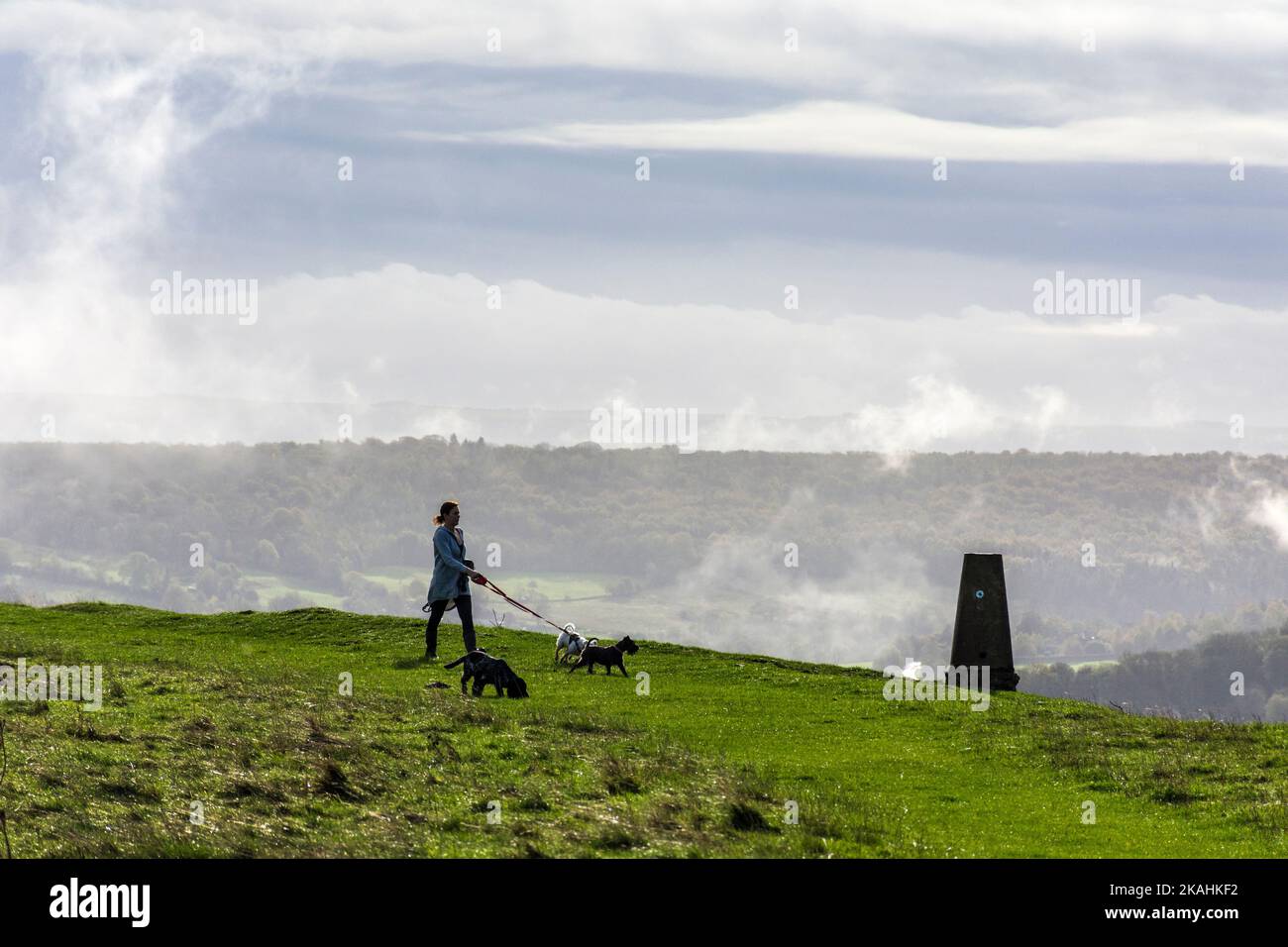 Batheaston, Somerset, UK weather. 3rd November 2022. A woman walks her dogs past the triangulation pillar atop Little Solsbury Hill after a night of heavy rainfall. Credit: Richard Wayman/Alamy Live News Stock Photo