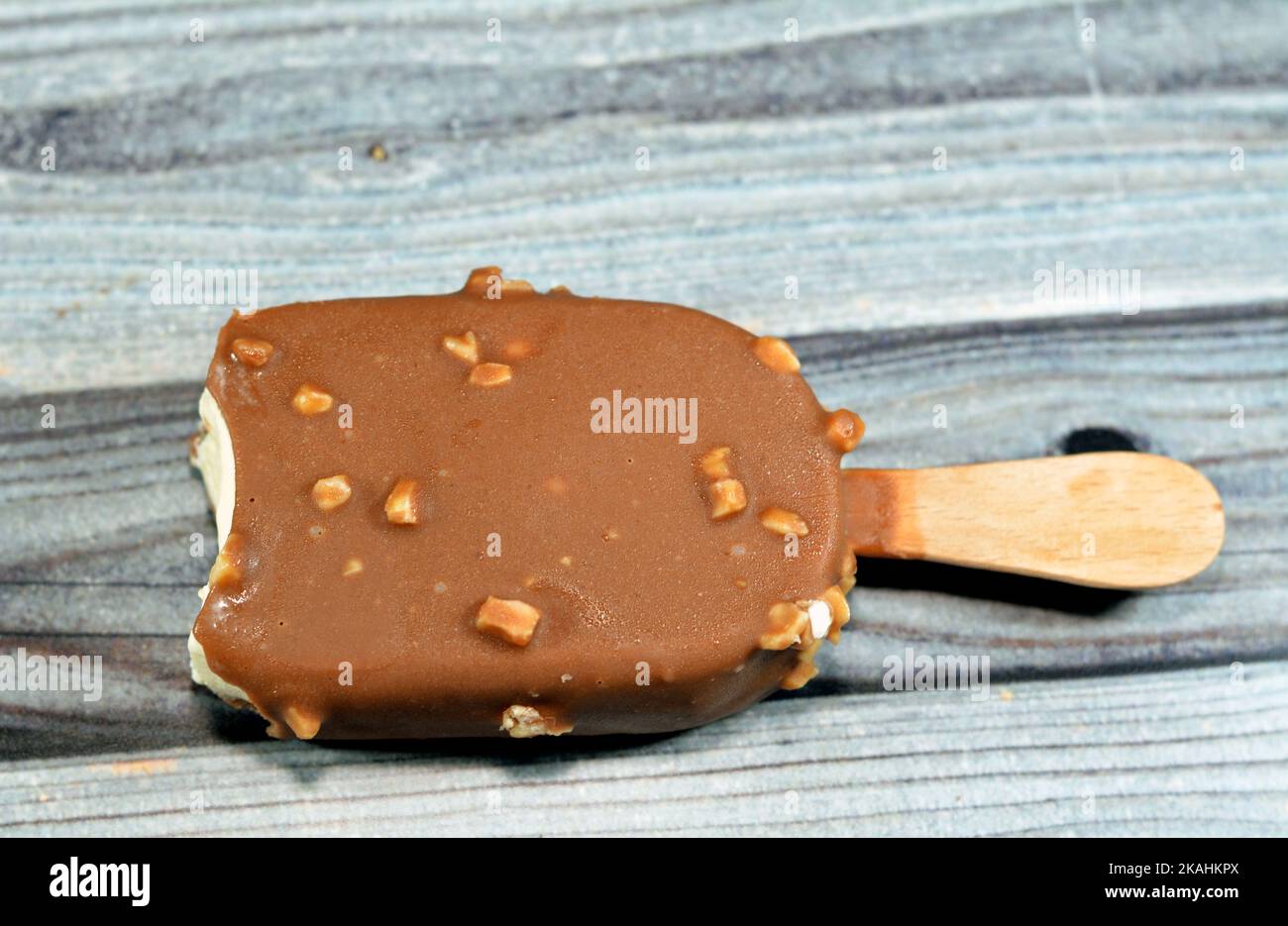 Rich vanilla flavored ice cream in cracking brown milk chocolate and roasted almond isolated, Vanilla ice cream stick coated and covered with a layer Stock Photo