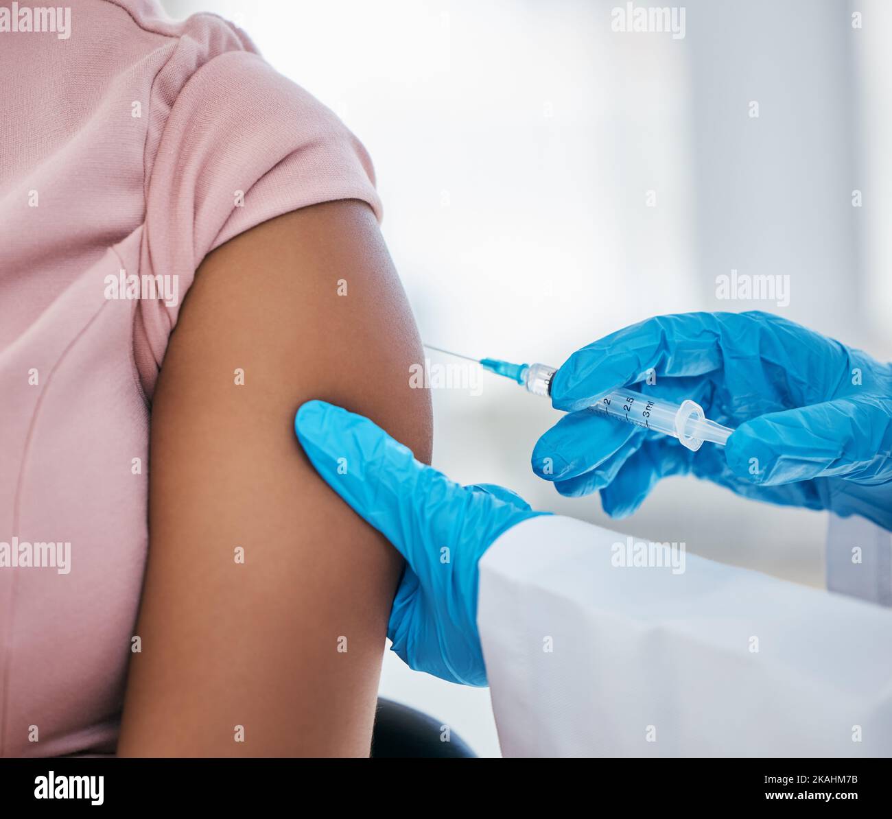 Healthcare, arm and covid vaccine by doctor in consultation room, compliance and gloves closeup. Hospital, hand and injection on woman patient, needle Stock Photo