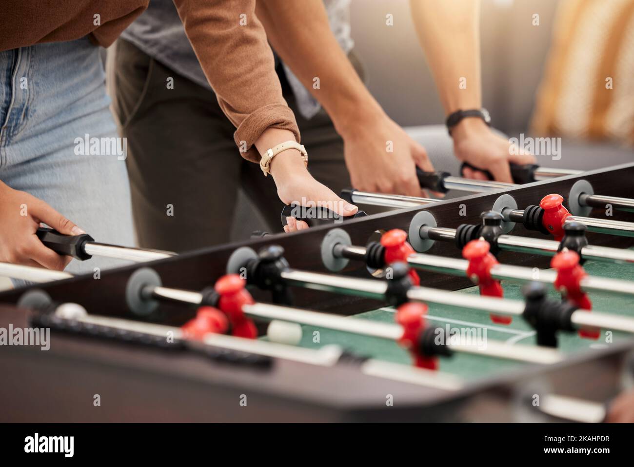 Hands, foosball and table with friends playing a game together indoors for fun or recreation