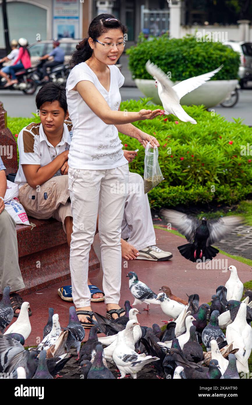 Vietnamese lady with pigeon in hand in public park, central Ho Chi Minh City, Vietnam Stock Photo