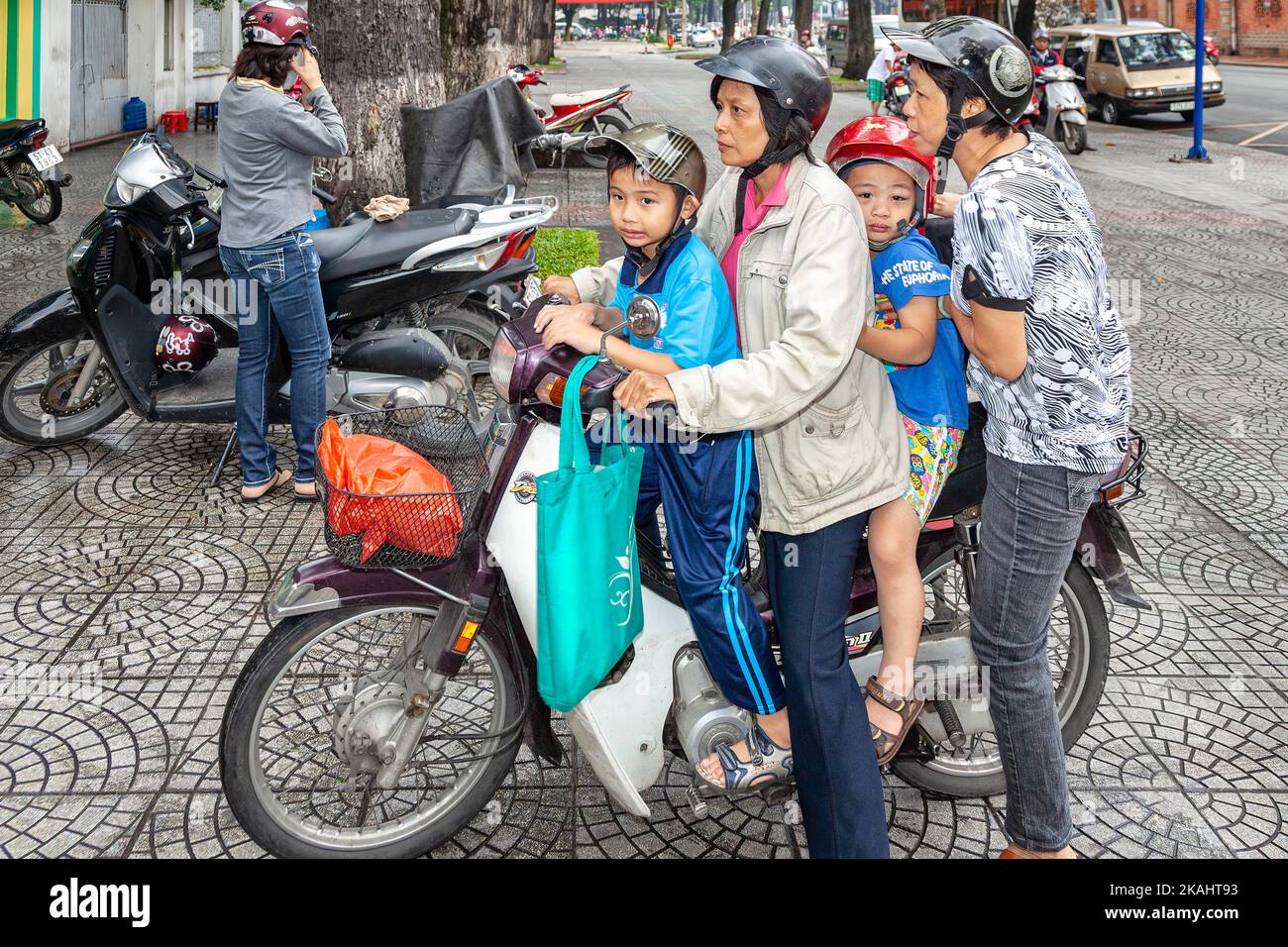 Vietnamese family of four people wearing helmets on motorcycle, Ho Chi Minh City, Vietnam Stock Photo