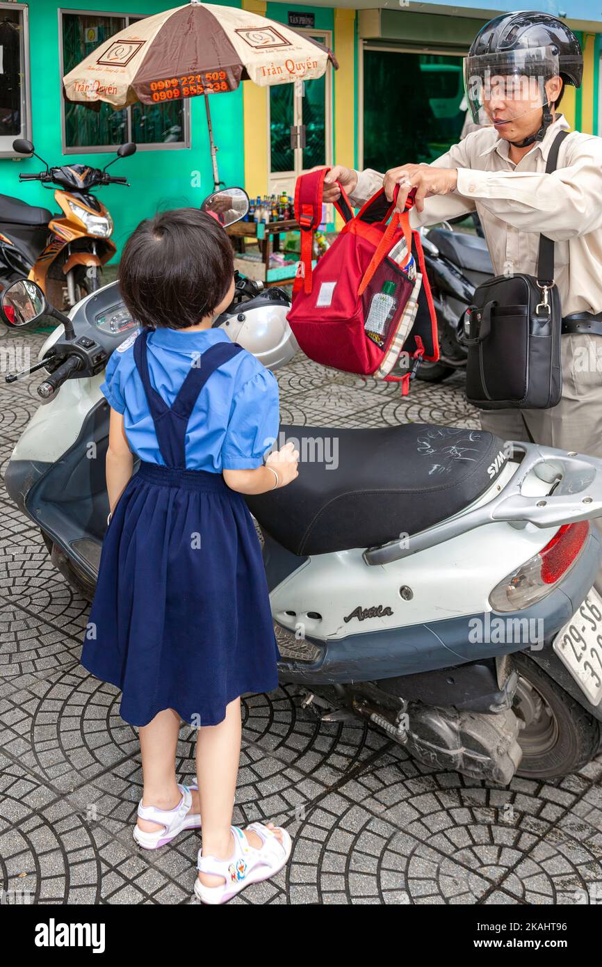 Vietnamese schoolgirl and father with backpack and scooter, Ho Chi Minh City, Vietnam Stock Photo