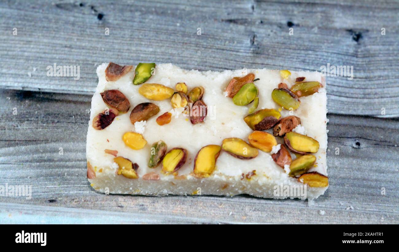 A piece of soft coconut Egyptian candy covered with pistachios