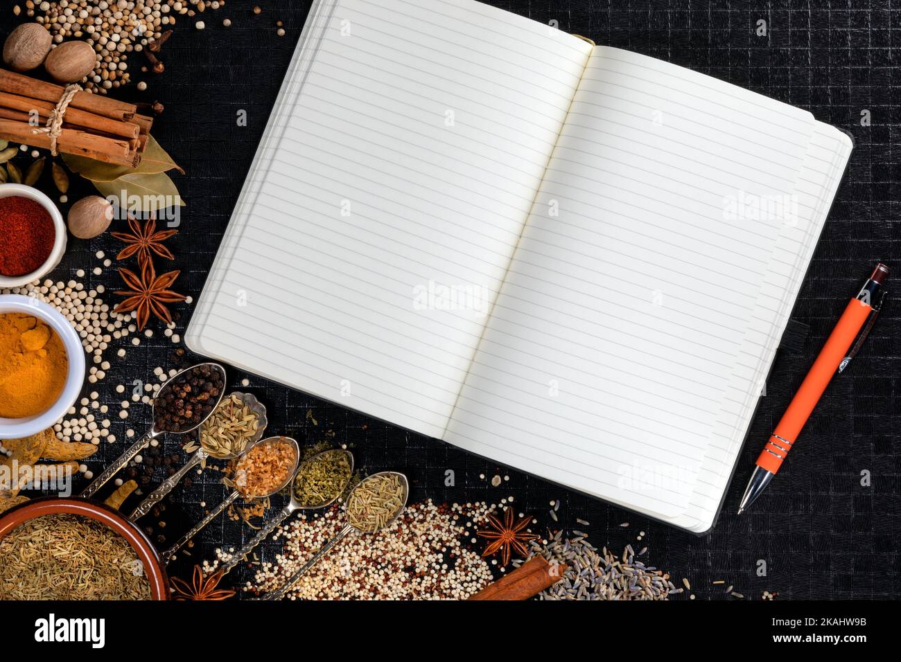 Cooking spices used to add flavor and seasoning with an open recipe book with blank pages - space for text. Stock Photo