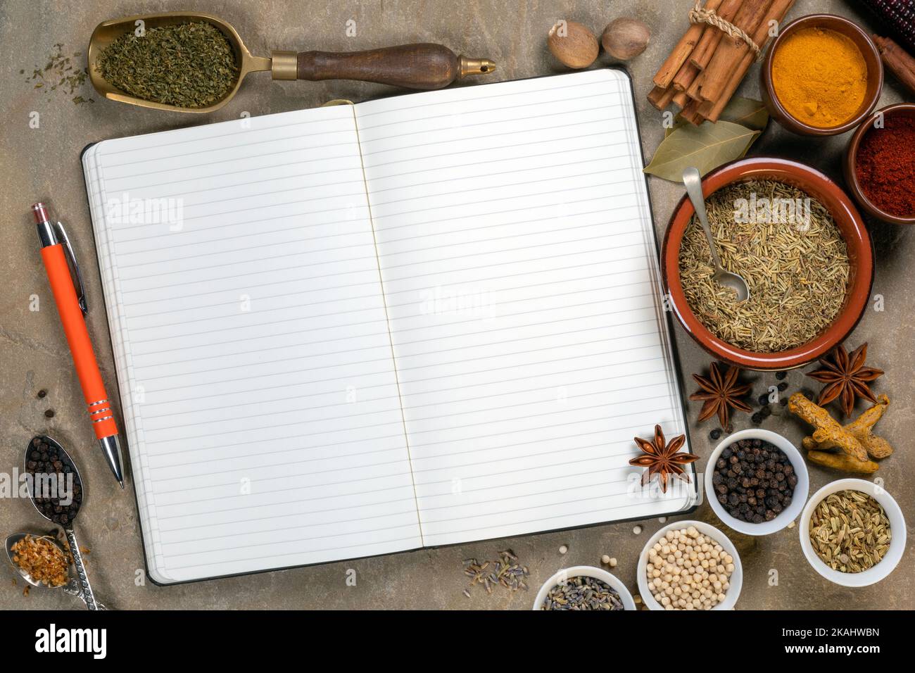 Cooking spices used to add flavor and seasoning with an open recipe book with blank pages - space for text. Stock Photo