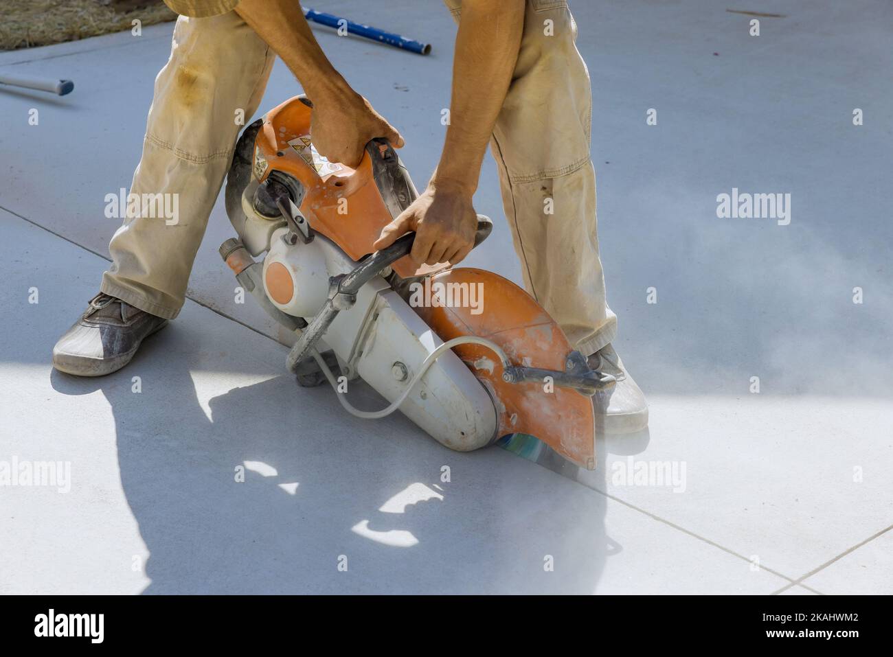 Concrete sidewalk is cut using diamond blade saw by construction worker Stock Photo