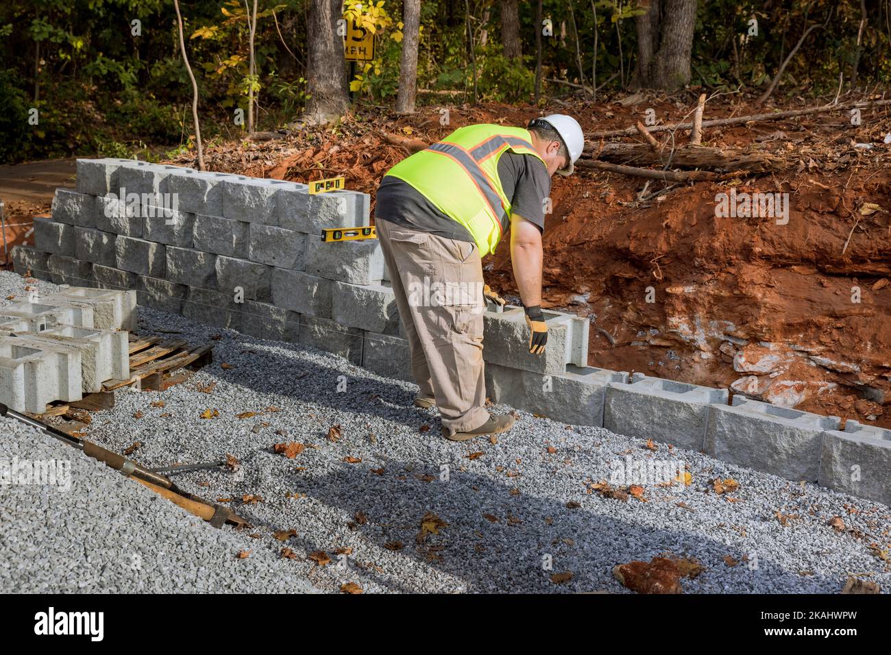 Construction worker building retaining block wall being built on new