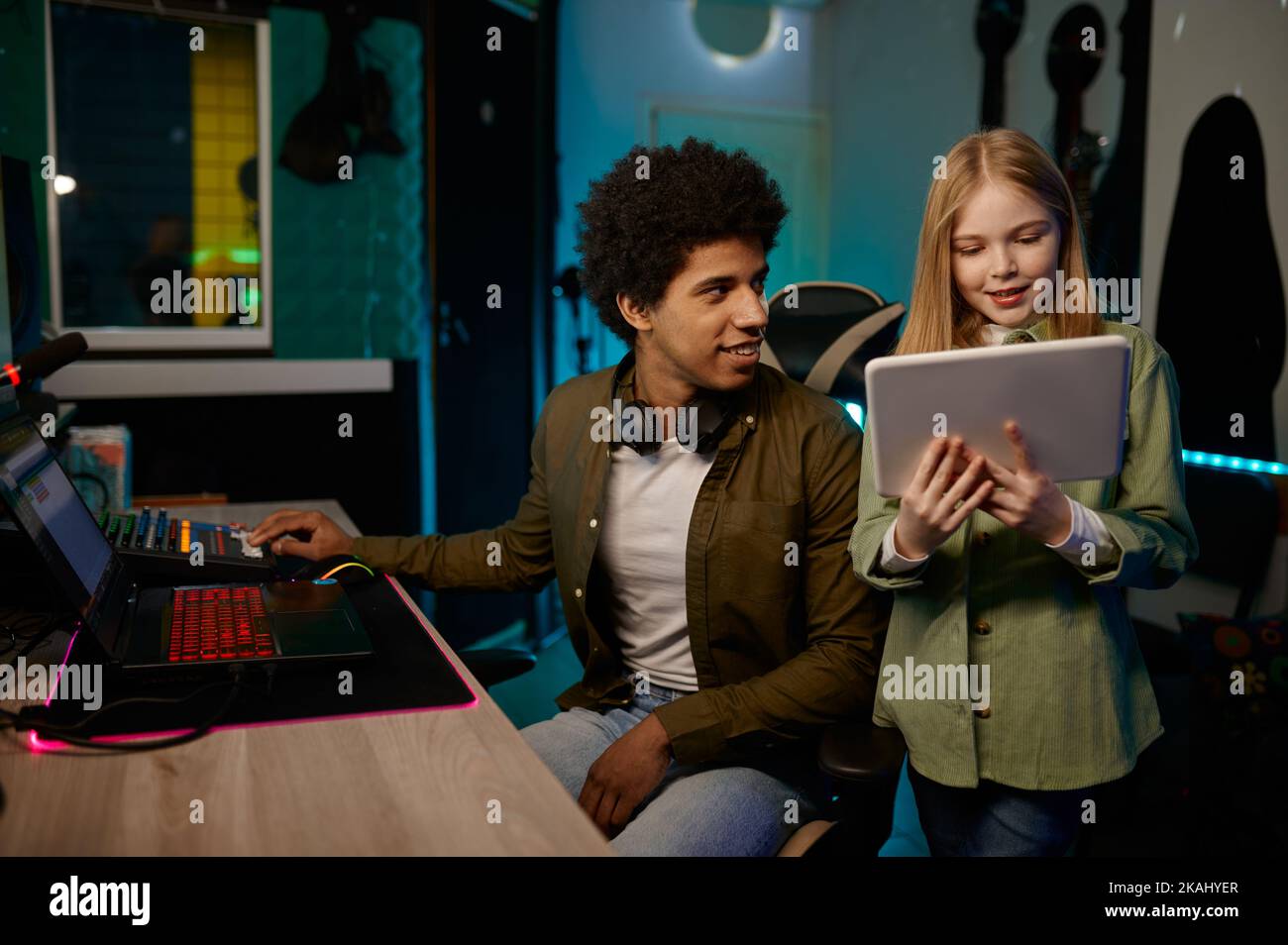 Audio engineer with young singer working in music recording studio