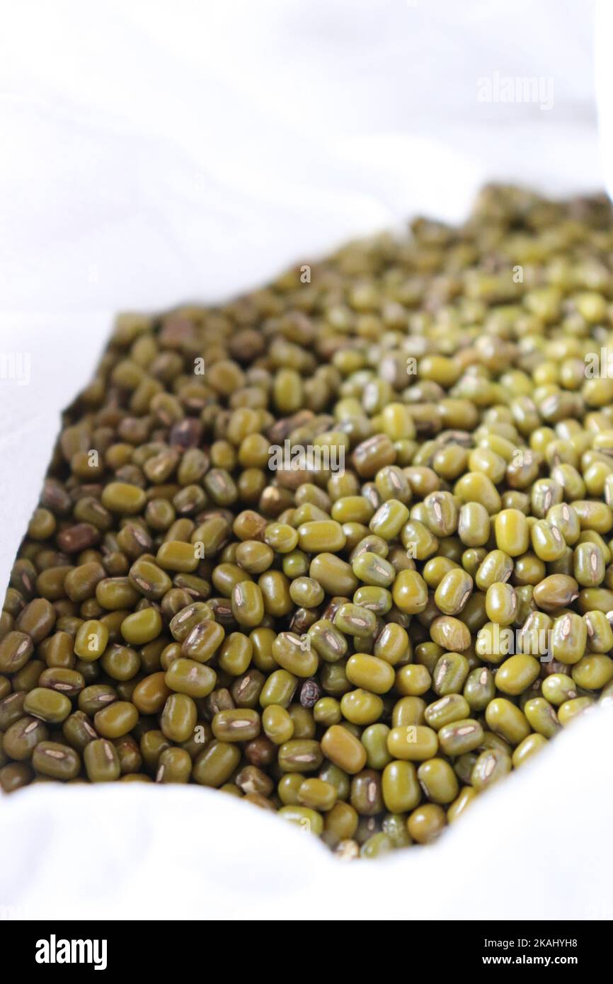 Close-up of Green gram/ Mung bean in a white bag against white background Stock Photo