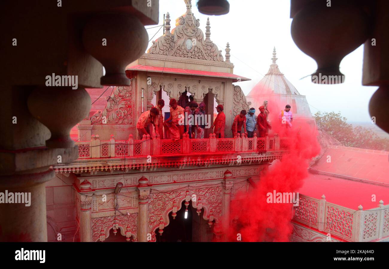 Indian hindu devotees throw colored powder at Radha Rani Temple during Lath mar Holi in Barsana, some 43 kms from Mathura on March 17,2016.During the Lathmar holi festival, women of Barsana ,legendary hometown of Radha, Consort of Hindu Lord Krishna, attack the men from Nandgaon, the home town of Lord Krishna, with wooden sticks in response, to their efforts to put color on them.  Stock Photo