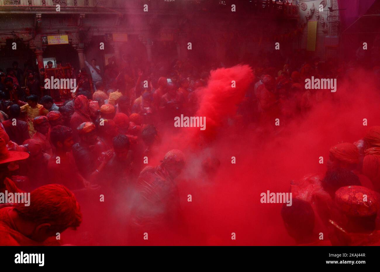 Indian hindu devotees throw colored powder at Radha Rani Temple during Lath mar Holi in Barsana, some 43 kms from Mathura on March 17,2016.During the Lathmar holi festival, women of Barsana ,legendary hometown of Radha, Consort of Hindu Lord Krishna, attack the men from Nandgaon, the home town of Lord Krishna, with wooden sticks in response, to their efforts to put color on them.  Stock Photo