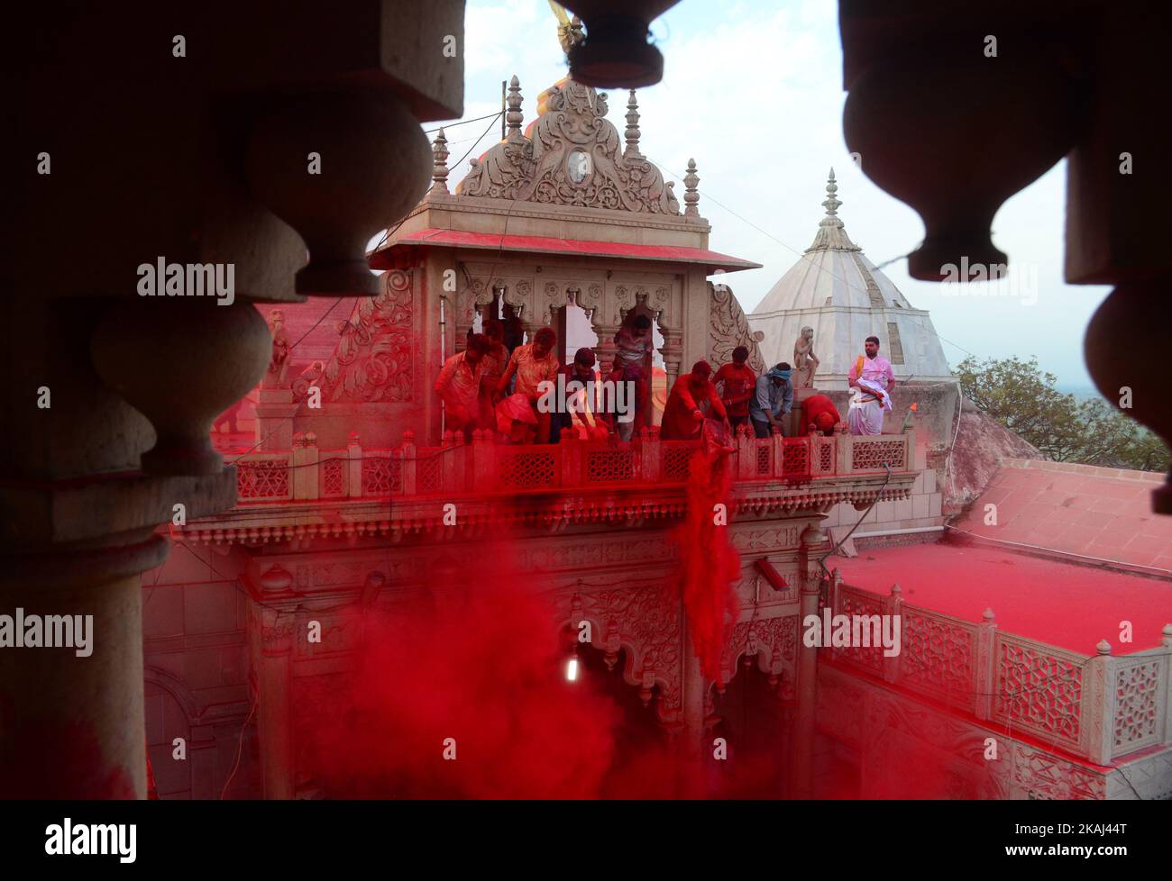 Indian hindu devotees throw colored powder at Radha Rani Temple during Lath mar Holi in Barsana, some 43 kms from Mathura on March 17,2016.During the Lathmar holi festival, women of Barsana ,legendary hometown of Radha, Consort of Hindu Lord Krishna, attack the men from Nandgaon, the home town of Lord Krishna, with wooden sticks in response, to their efforts to put color on them.  Stock Photo