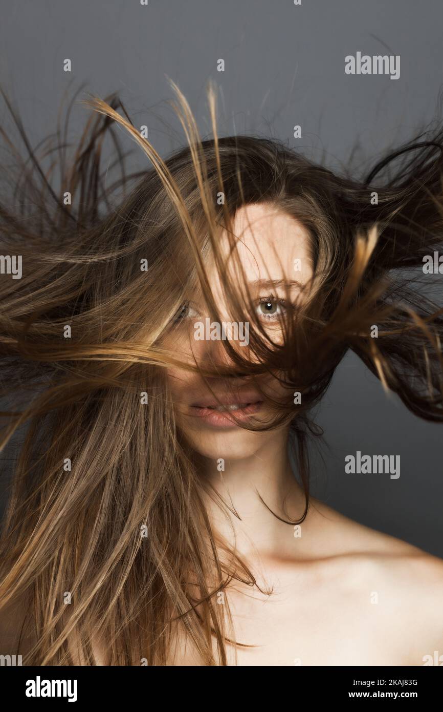 girl with flowing hair in the air studio portrait against gray
