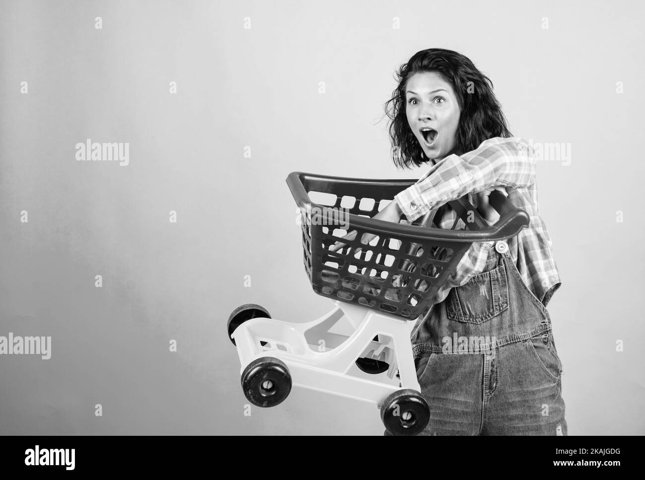 woman shopping in supermarket pushing trolley. happy girl hold shopping