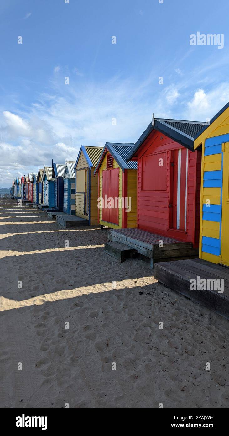 A vertical shot of colorful huts in a row on a beach Stock Photo