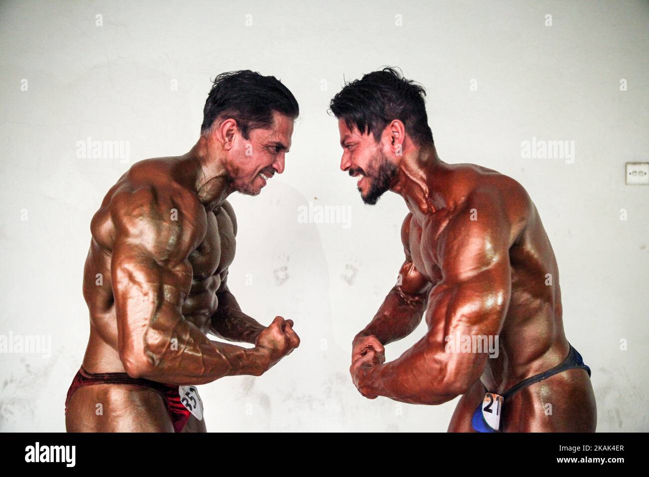 Two bodybuilders pose infront of the camera and show their muscles, in