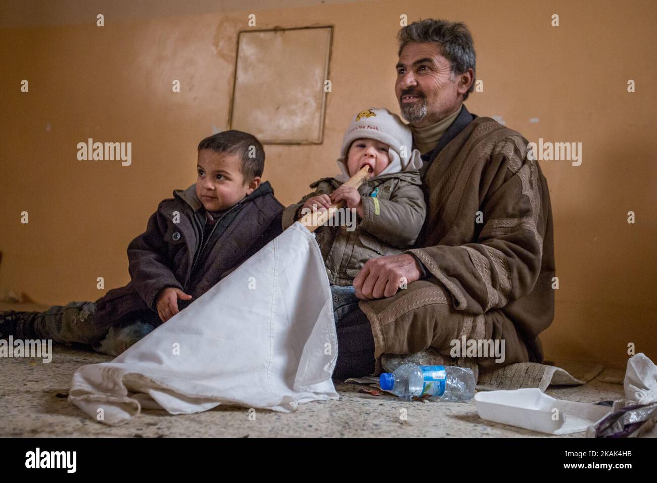 (12/2/2016) Hashem Abani (50) with his children after escaping the fighting between Iraqi army and ISIS, they have reached the liberated district of Hay Samah, on the eastern outskirts of Mosul / Iraq. One of his sons holds the white flag, which they still use to make themselves known as civilians. (Photo by Sebastian Backhaus/NurPhoto) *** Please Use Credit from Credit Field *** Stock Photo