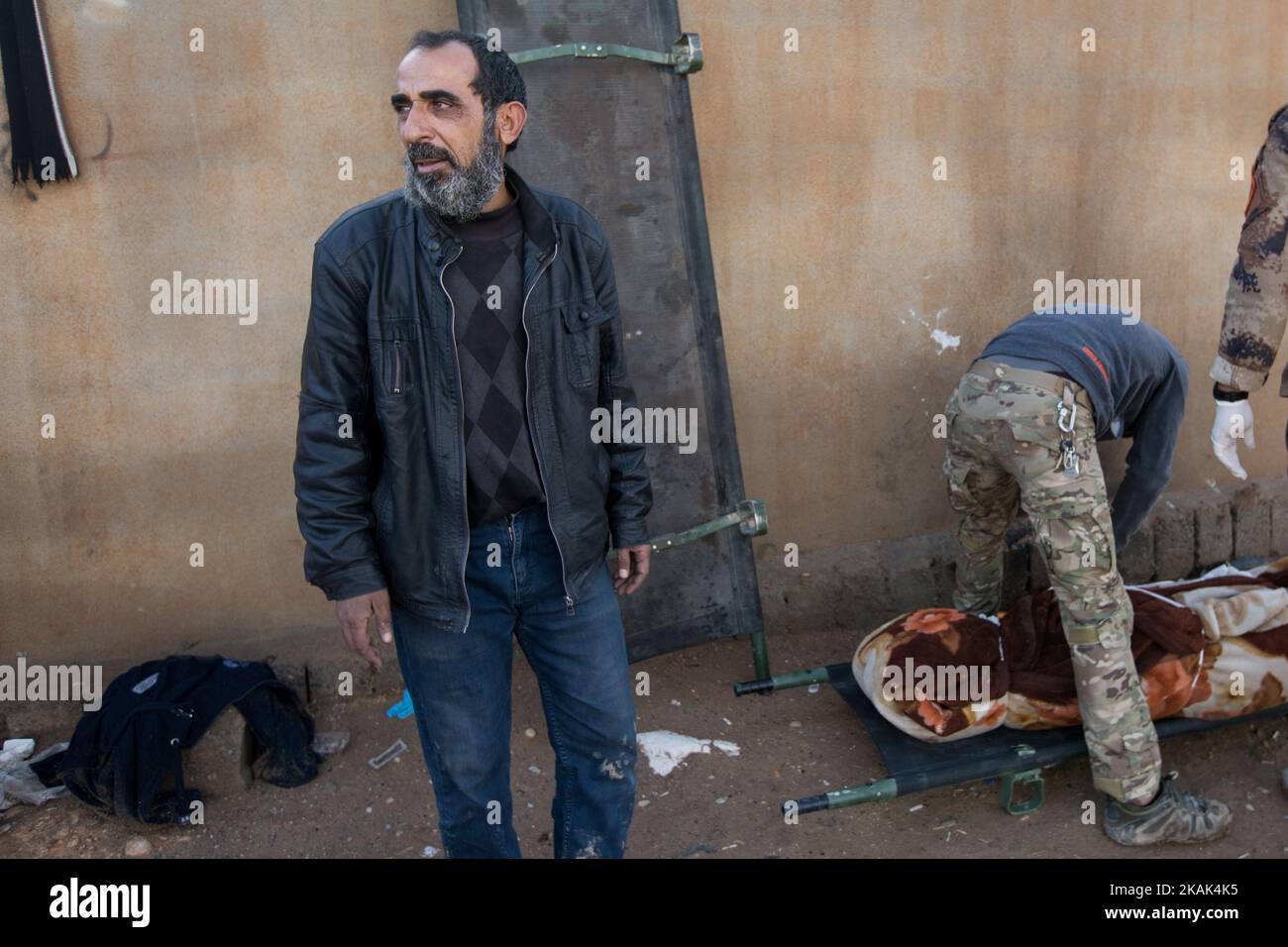 (12/2/2016) Jabar in front of the field hospital in the liberated district of Hay Samah, on the eastern outskirts of Mosul / Iraq after a rocket hit his house. Next to him, paramedics cover the body of his mother, who was killed in the attack. (Photo by Sebastian Backhaus/NurPhoto) *** Please Use Credit from Credit Field *** Stock Photo