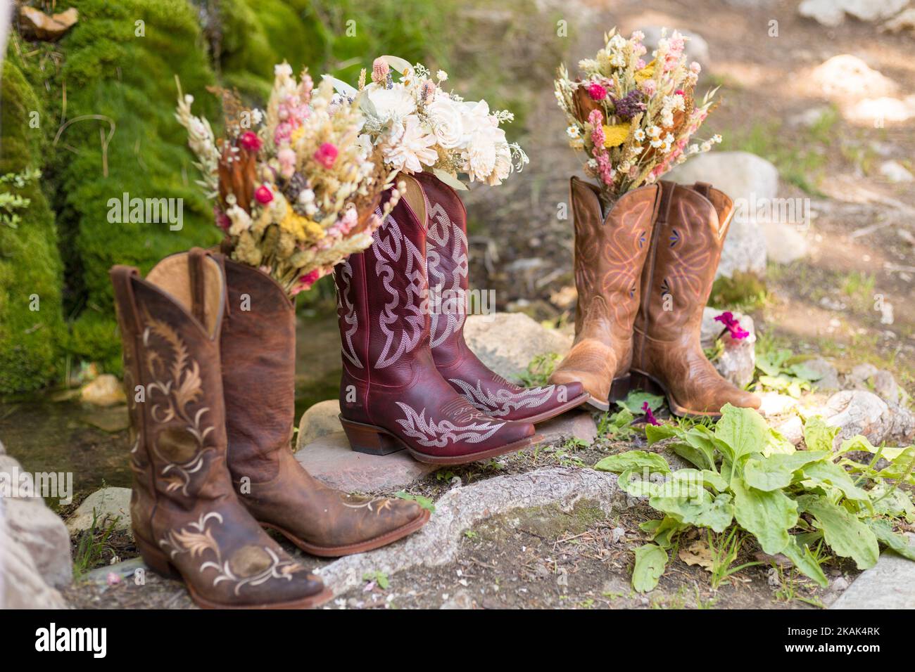 Colorful wedding Day flowers in three pairs of women cowboy boots for bride and bridesmaids Stock Photo