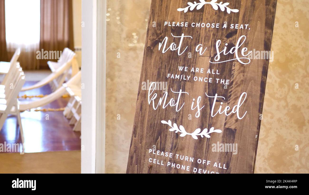 Please choose a seat, not a side, we are all family once the knot is tied sign on Wedding Day Stock Photo