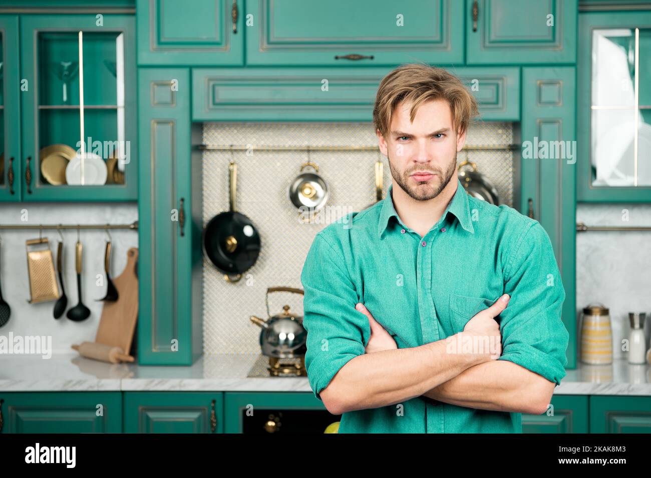 Macho with serious face stand with folded hands in kitchen Stock Photo ...