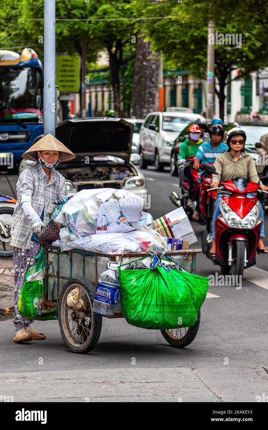 Vietnamese woman wearing bamboo hat, recycling waste with pushcart, Ho Chi Minh City, Vietnam Stock Photo