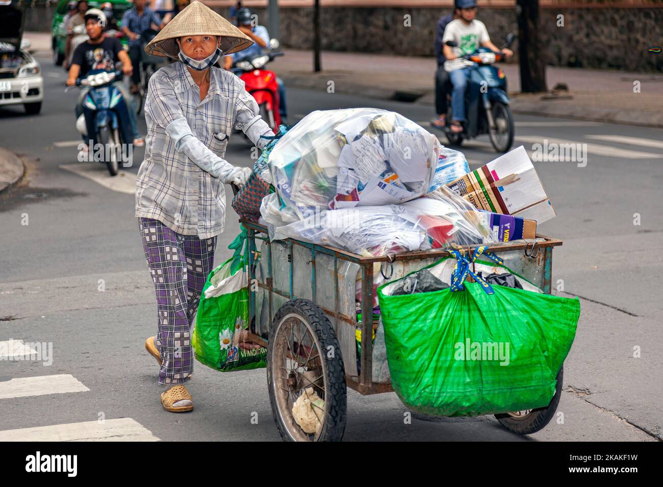 Vietnamese woman wearing bamboo hat, recycling waste with pushcart, Ho Chi Minh City, Vietnam Stock Photo