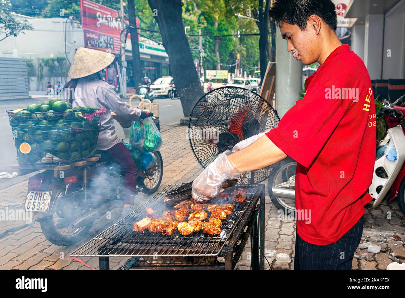Vietnamese man cooking at roadside barbecue in street market, Ho Chi Minh City, Vietnam Stock Photo