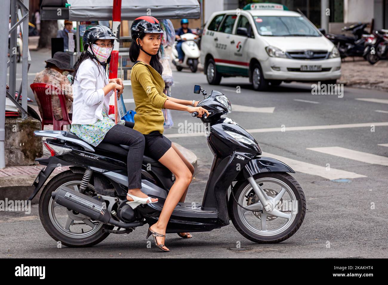 Attractive Vietnamese girls riding on motorcycle in traffic, Ho Chi Minh City, Vietnam Stock Photo