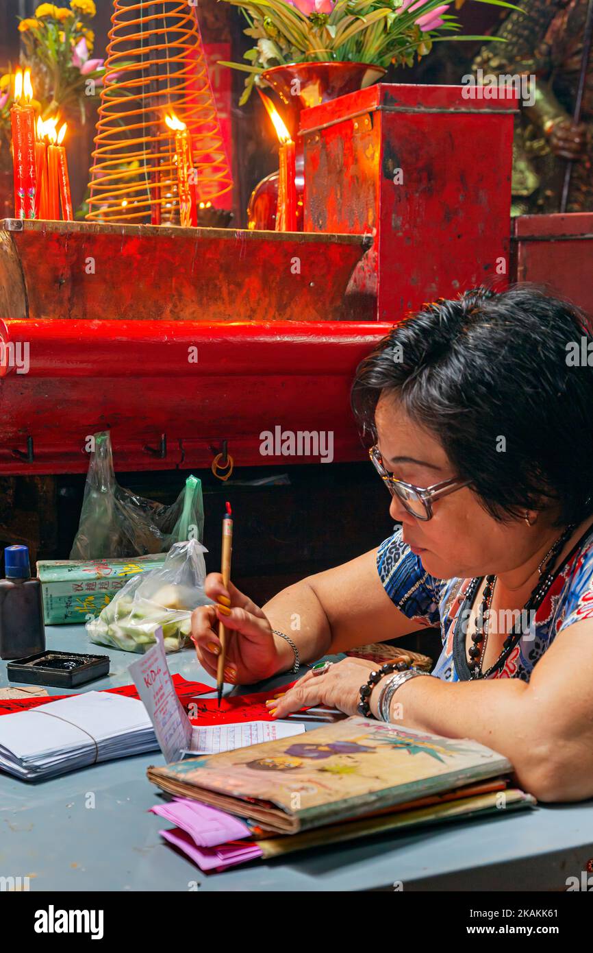 Vietnamese fortune teller writing inscription inside Jade Empress Pagoda, Ho Chi Minh City, Vietnam Stock Photo