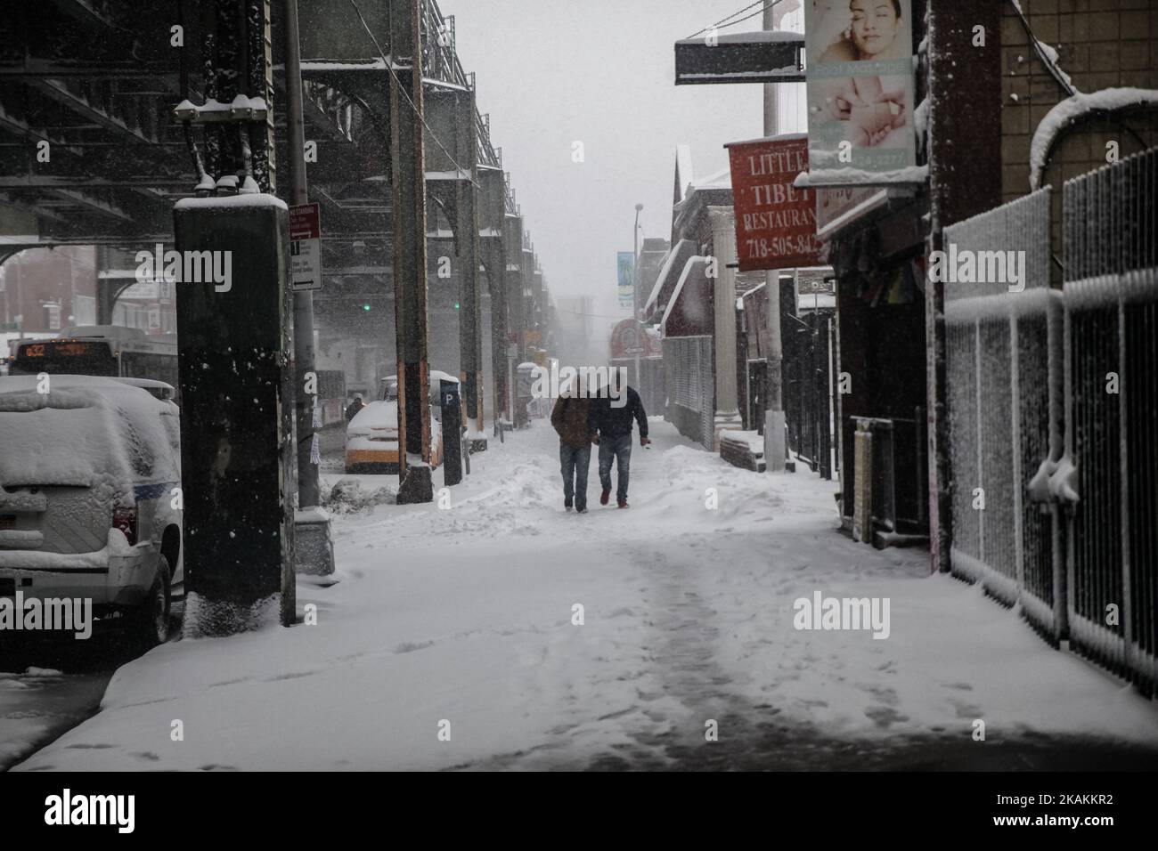 Two friends walks carefully during an early morning heavy snowfall at