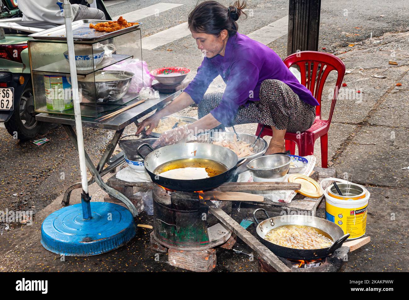 Vietnamese lady cooking food at roadside restaurant, Ho Chi Minh City, Vietnam Stock Photo