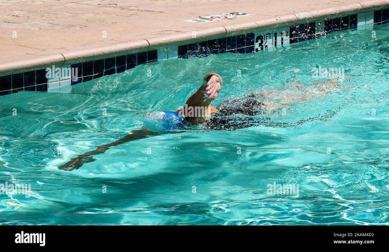One female swimmer swimming laps in an outdoor pool at a hotel wearing