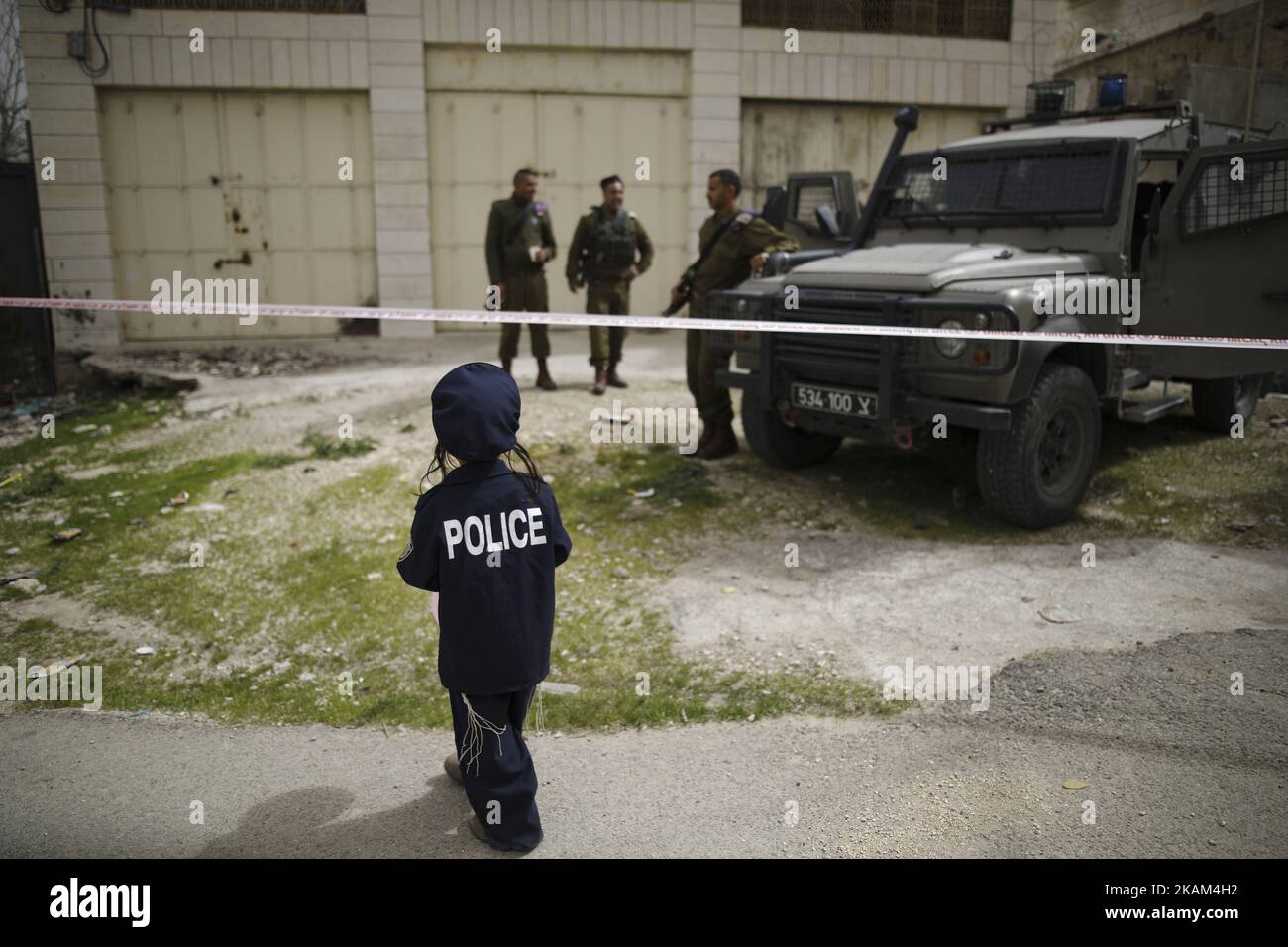 A young Jewish settler dressed as a policeman watches Israeli soldiers during the annual Purim parade, in the Jewish sector of the West Bank city of Hebron, 12 March 2017. The Jewish holiday of Purim is a celebration of the Jews' salvation from genocide in ancient Persia, as recounted in the Scroll of Esther. (Photo by Corinna Kern/NurPhoto) *** Please Use Credit from Credit Field *** Stock Photo