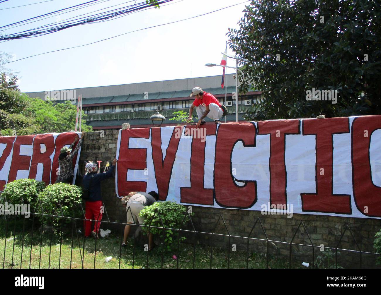 Protesters from an urban poor group unfurl a banner that reads, 'ZERO EVICTION' outside the National Housing Authority in Quezon City, Philippines on Monday, March 20, 2017, during a rally against a planned serving of an eviction notice to occupiers of a vacant housing project in Bulacan province. An urban poor group organized an occupation of several vacant government housing projects in Bulacan province on March 8, 2017 to protest the Philippine government's alleged failure to provide housing to its people, with authorities warning the group and its members to voluntarily go away, or face a  Stock Photo