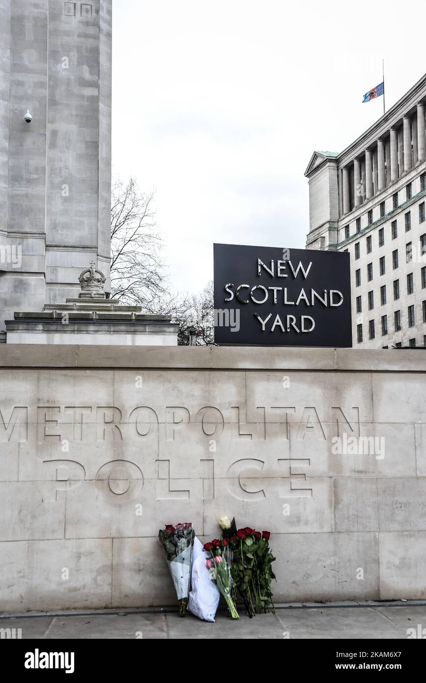 Floral tributes sit outside New Scotland Yard following yesterday's attack in which one police officer was killed on March 23, 2017 in London, England Police continue investigations after the terror attack in London yesterday in which a car was driven into pedestrians on Westminster Bridge and then into railings outside the Houses of Parliament, where a knifeman stabbed a police officer named as PC Keith Palmer, who subsequently died from his injuries. The attacker also died after security forces shot him. Two other people died in the incident and approx 40 were injured, some 'catastrophically Stock Photo