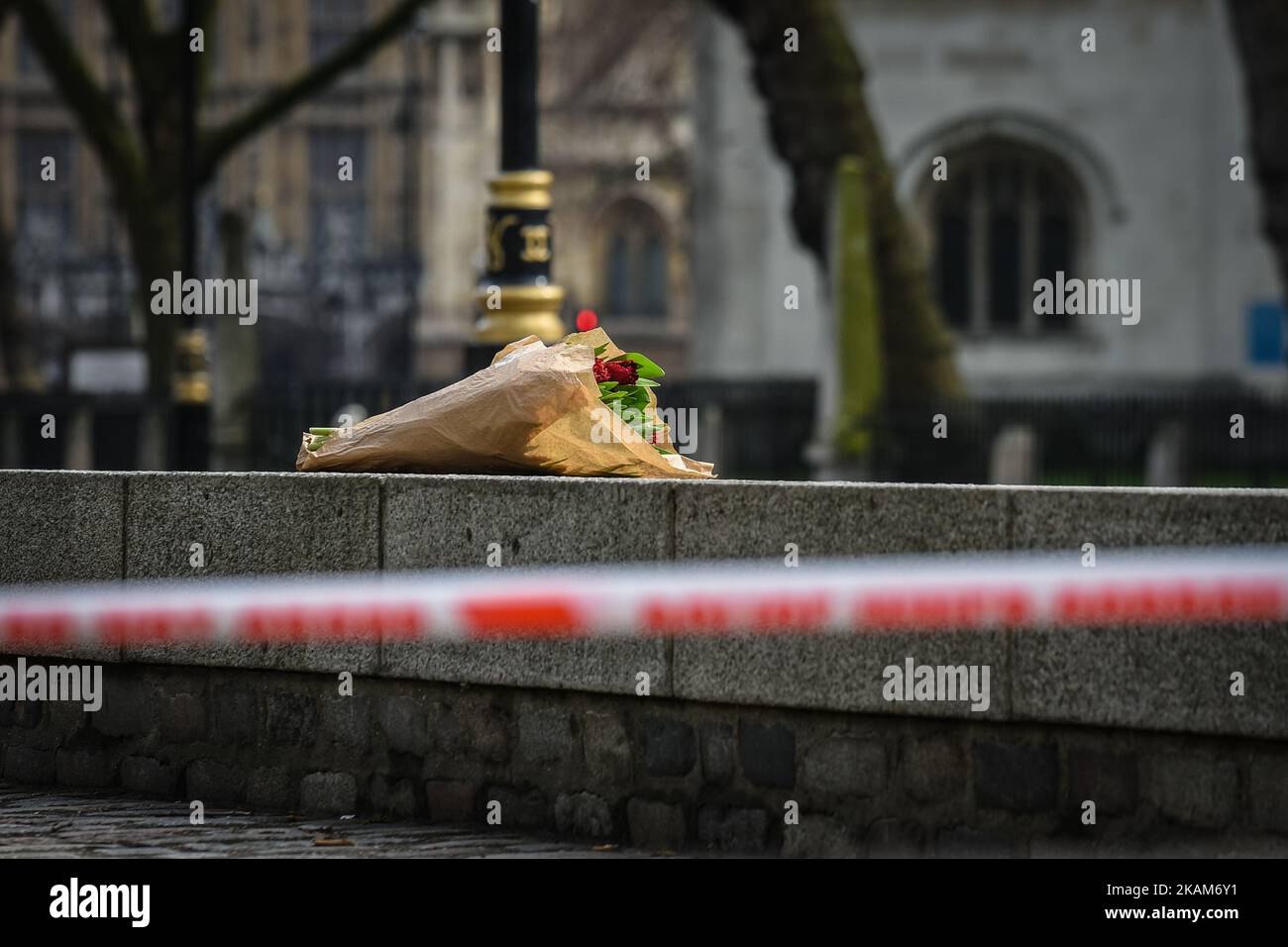 Floral tributes are seen near a police cordon in Westminster in London, on March 23, 2017. Police continue investigations after the terror attack in London yesterday in which a car was driven into pedestrians on Westminster Bridge and then into railings outside the Houses of Parliament, where a knifeman stabbed a police officer named as PC Keith Palmer, who subsequently died from his injuries. The attacker also died after security forces shot him. Two other people died in the incident and approx 40 were injured, some 'catastrophically'. A woman was pulled alive from the Thames after reportedly Stock Photo