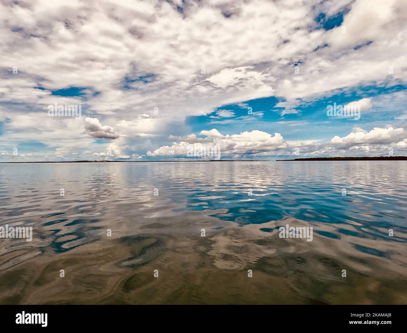 A mesmerizing cloudy sky over a lake reflected in the water Stock Photo ...