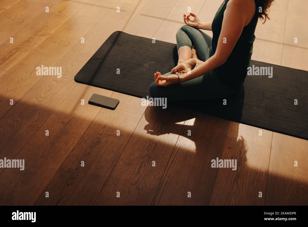 High angle view of a senior woman meditating while sitting in easy pose. Mature woman doing a relaxation exercise during a session of hatha yoga. Woma Stock Photo