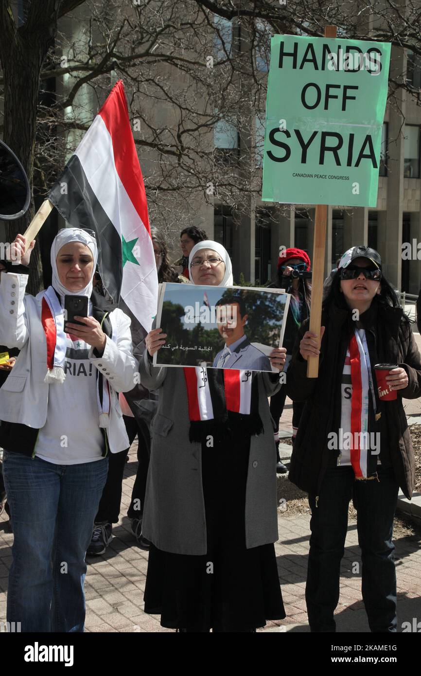 Syrian woman holds a poster of Syrian President Bashar al-Assad during a protest against US President Donald Trump's decision to launch airstrikes against Syria on April 8, 2017 in Toronto, Ontario Canada. Protestors gathered to outside the American Consulate in Toronto to denounce this week's airstrikes against the Syrian regime. America launched a missile strike against Syria for the first time since the civil war began, targeting an airbase in the small town of Idlib from which the United States claims this week’s chemical weapons attack on civilians was launched by Bashar al-Assad’s regime Stock Photo