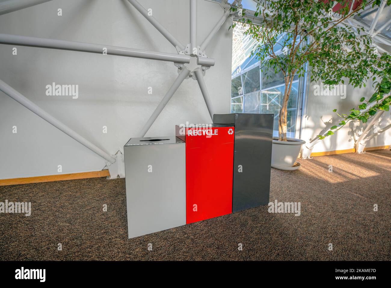 Three trash bins on a brown granite flooring inside a building in