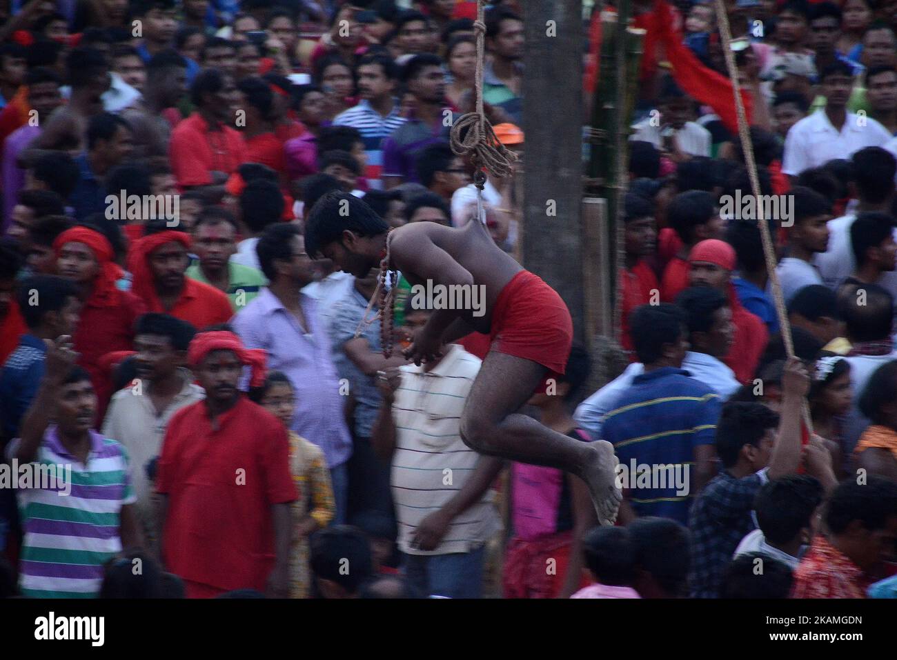 Indian Hindu devotee hanged from rope with iron hook during the Gajan