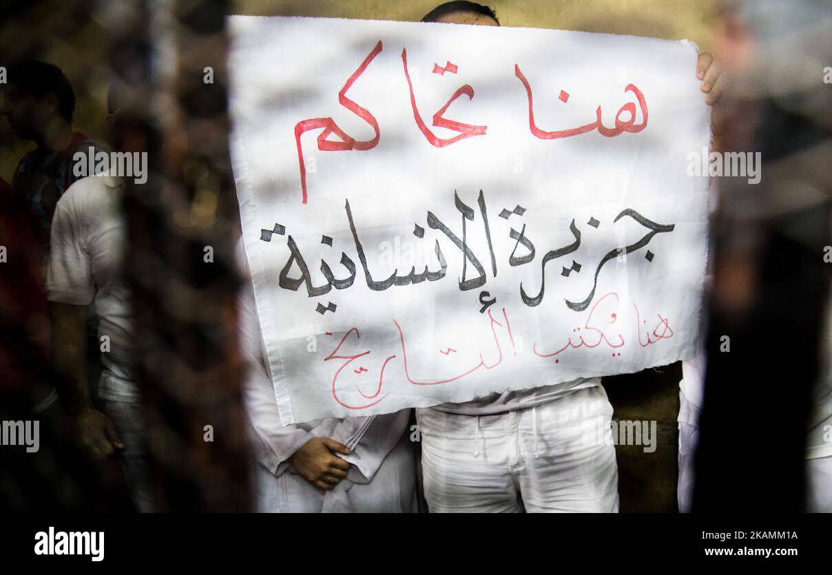 Founder of the Beladi Foundation in Egypt, Egyptian-American Aya Hegazy (L) and her husband Mohamed Hussanain (R) show a banner of protest inside the defendent's cage after being acquitted by an Egyptian court, Cairo, Egypt, 16 April 2017. (Photo by Asmaa Gamal/NurPhoto) *** Please Use Credit from Credit Field *** Stock Photo
