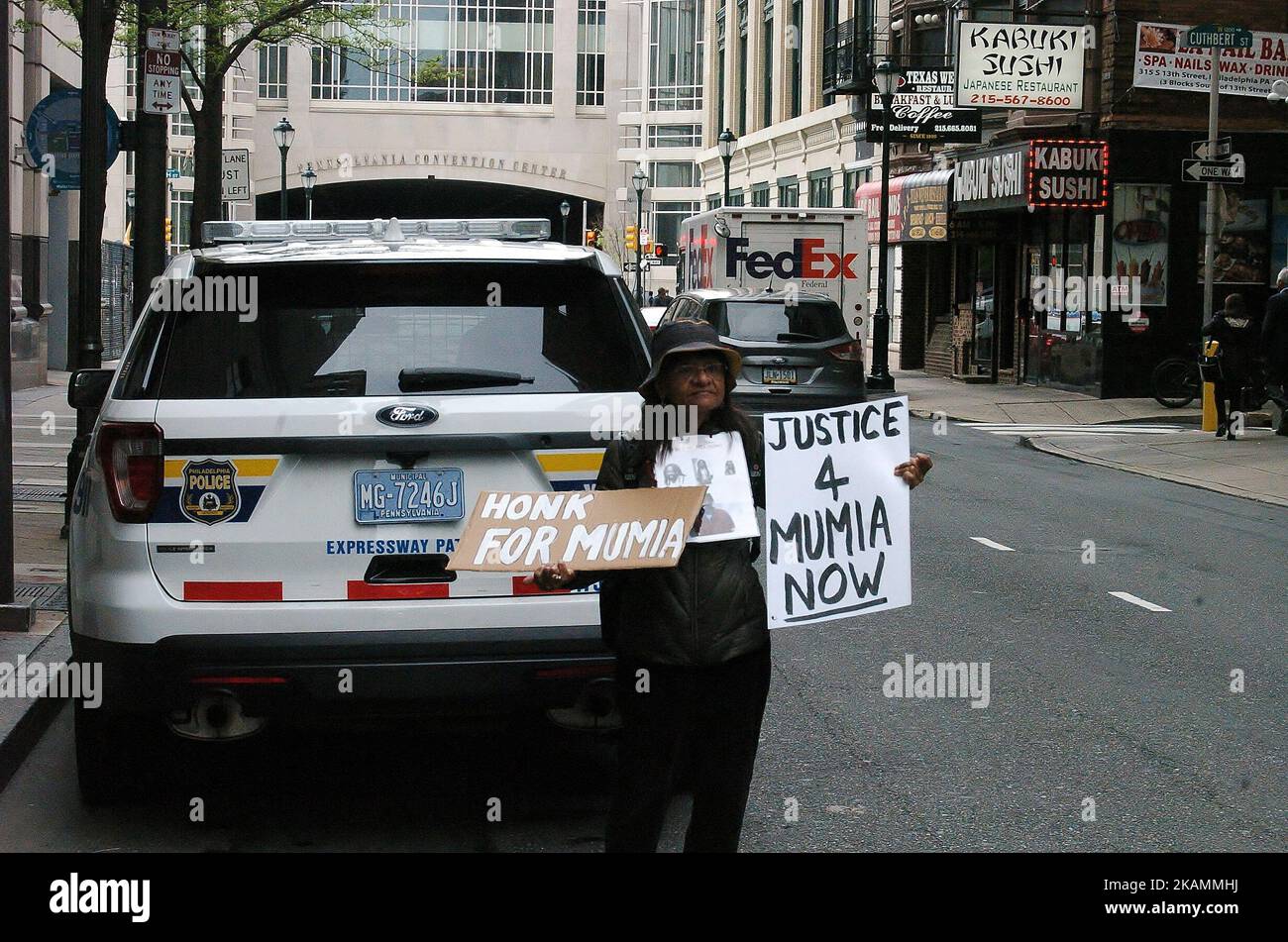 A protester stands behind a police care with signs demanding the release of and support for Mumia Abu-Jamal in Philadelphia, PA on April 24, 2017 Mumia was convicted in 1981 of the murder of police officer Daniel Faulkner. His supporters around the world hold firm that the conviction was wrongful and that the prosecution both fabricated evidence and withheld exculpatory evidence in the case against Mumia. (Photo by Cory Clark/NurPhoto) *** Please Use Credit from Credit Field *** Stock Photo