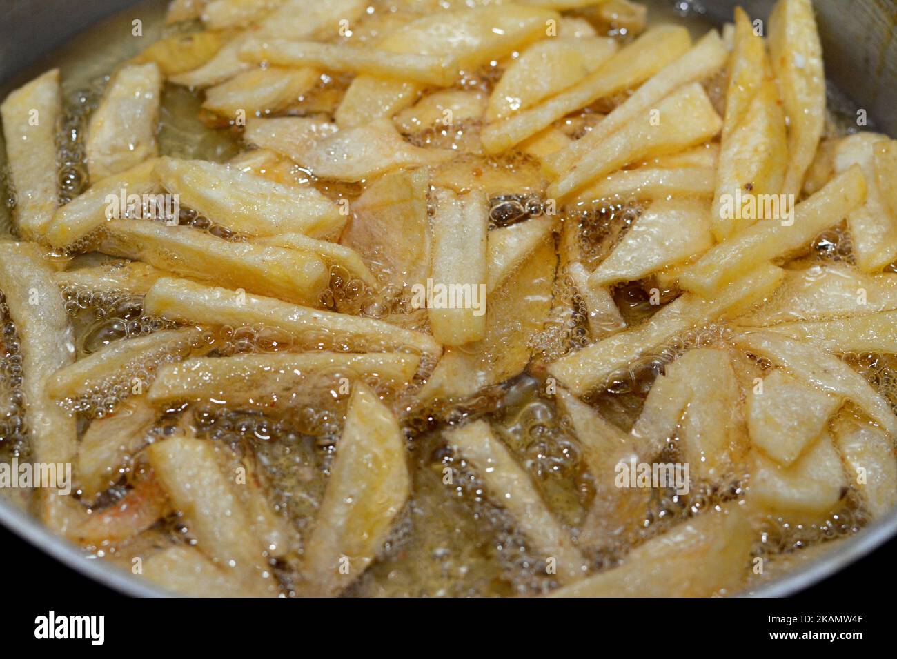 Closeup of French fries potatoes frying in boiling hot oil in a deep
