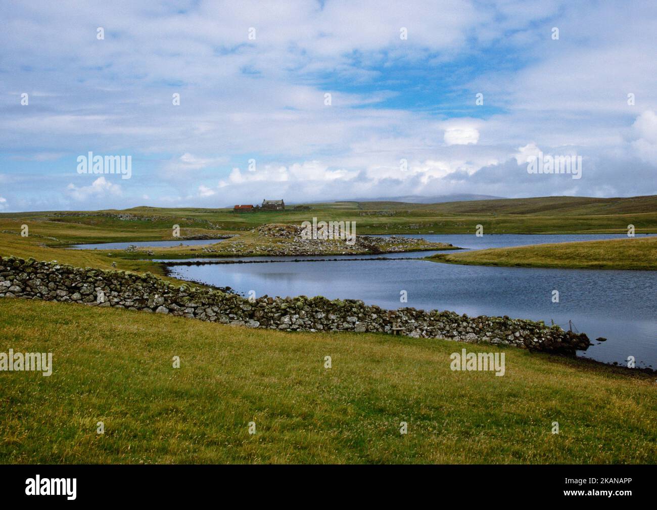 Loch of Houlland Iron Age broch built on a short promontory jutting from the W shore, Shetland, Scotland, UK, looking NE to Priesthoulland farmhouse. Stock Photo