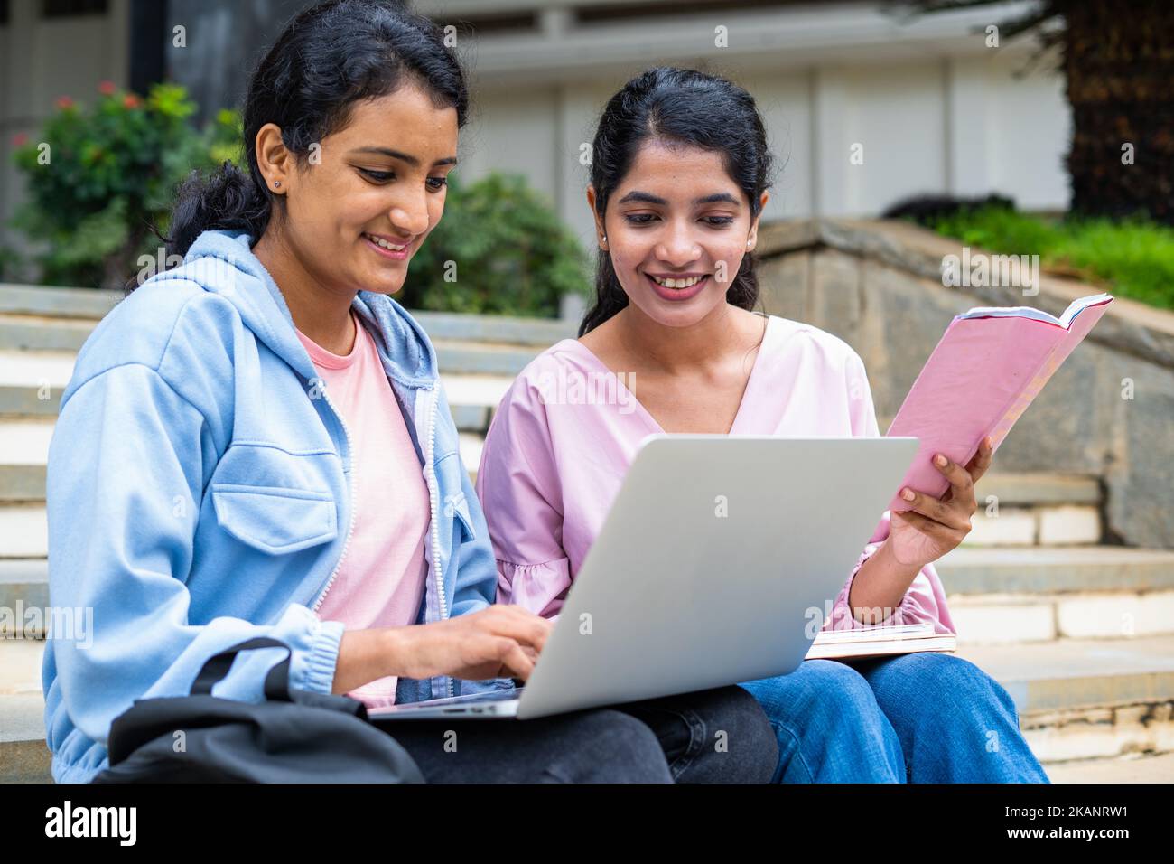 focus on girl with book, Happy College students busy working on laptop while sitting on campus - concept of education, technology and friendship Stock Photo