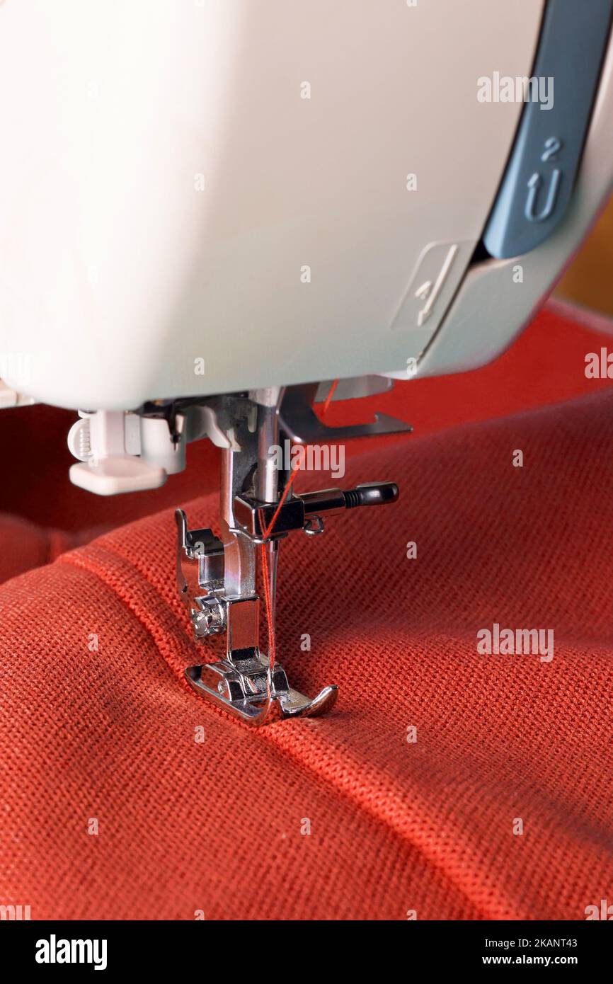Modern sewing machine working with red fabric. Sewing process Stock